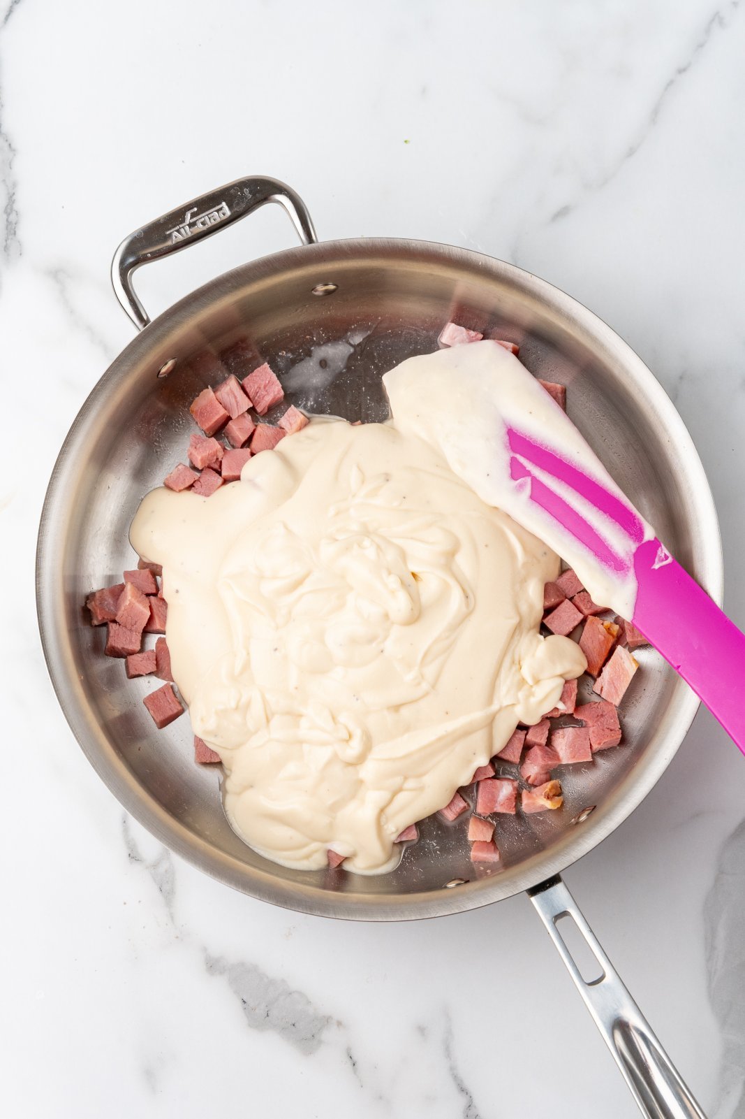 a larger skillet with ham and alfredo