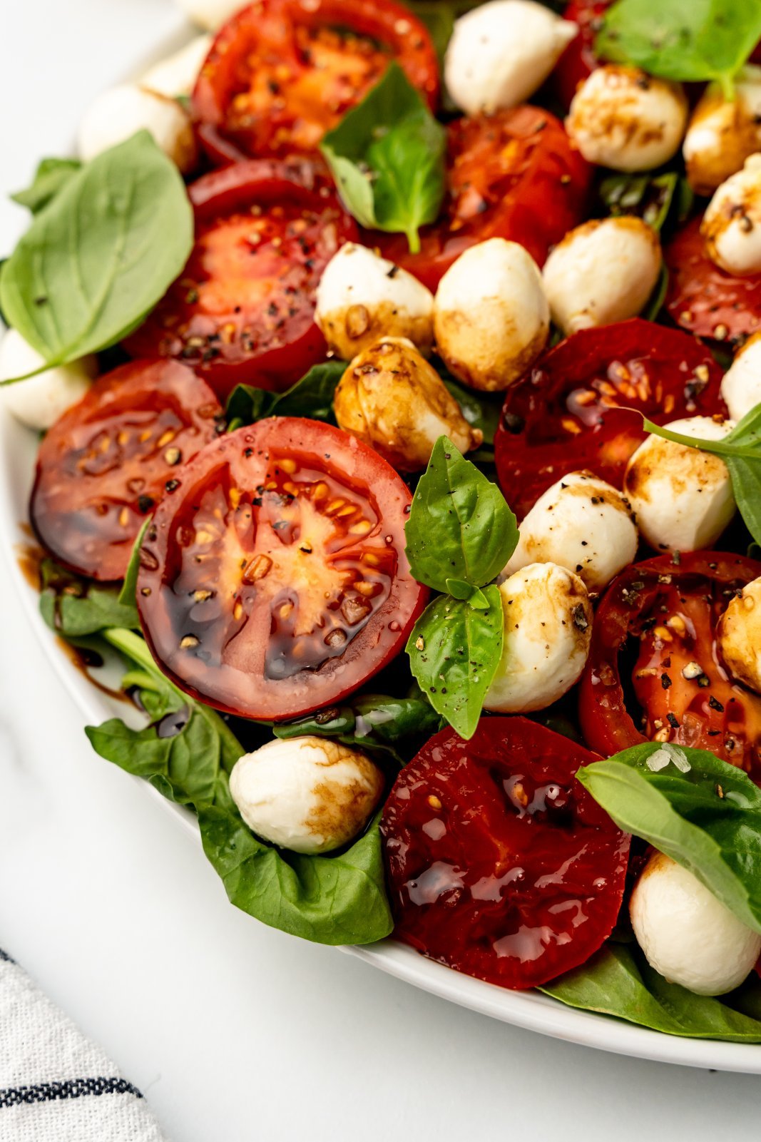 a close up of a tomato in the caprese spinach salad