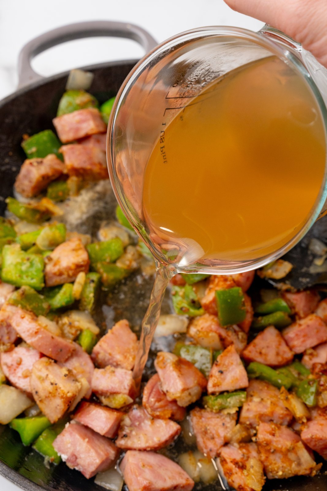 Chicken broth being poured into a skillet