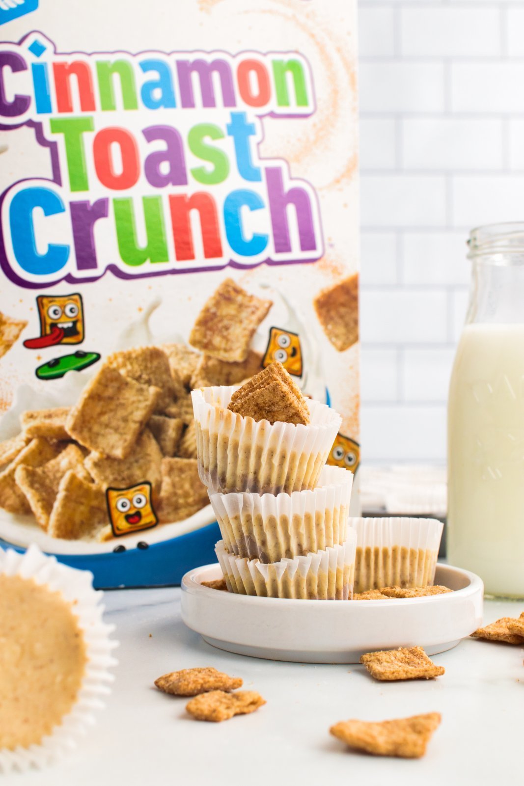 cheesecakes stacked on a plate with a cinnamon toast crunch box in the background, cereal scattered around