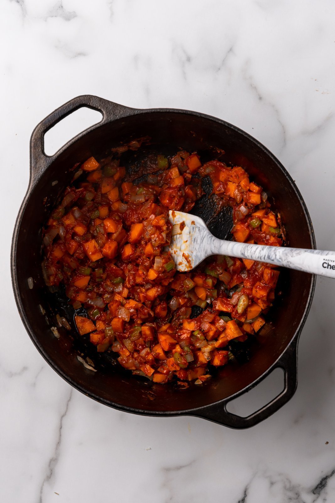 a view of onion, celery and carrot in the soup pot mixed with tomato paste
