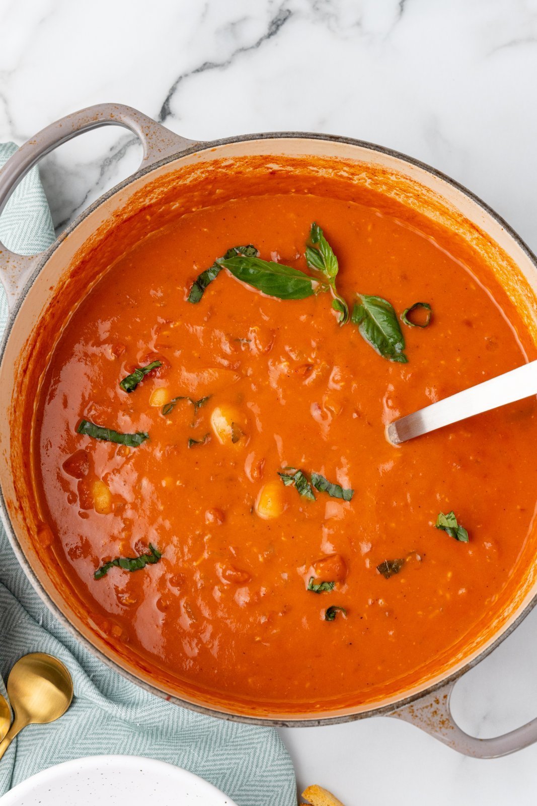 a view of the pot of soup woth basil sprinkled on top