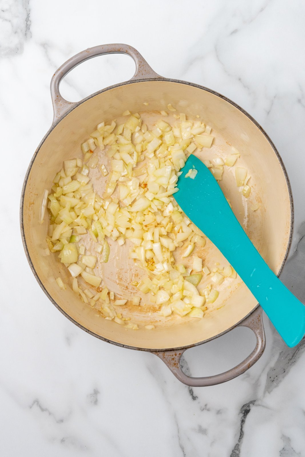 olive oil onion and garlic after cooking in the bottom of a large grey dutch oven pot