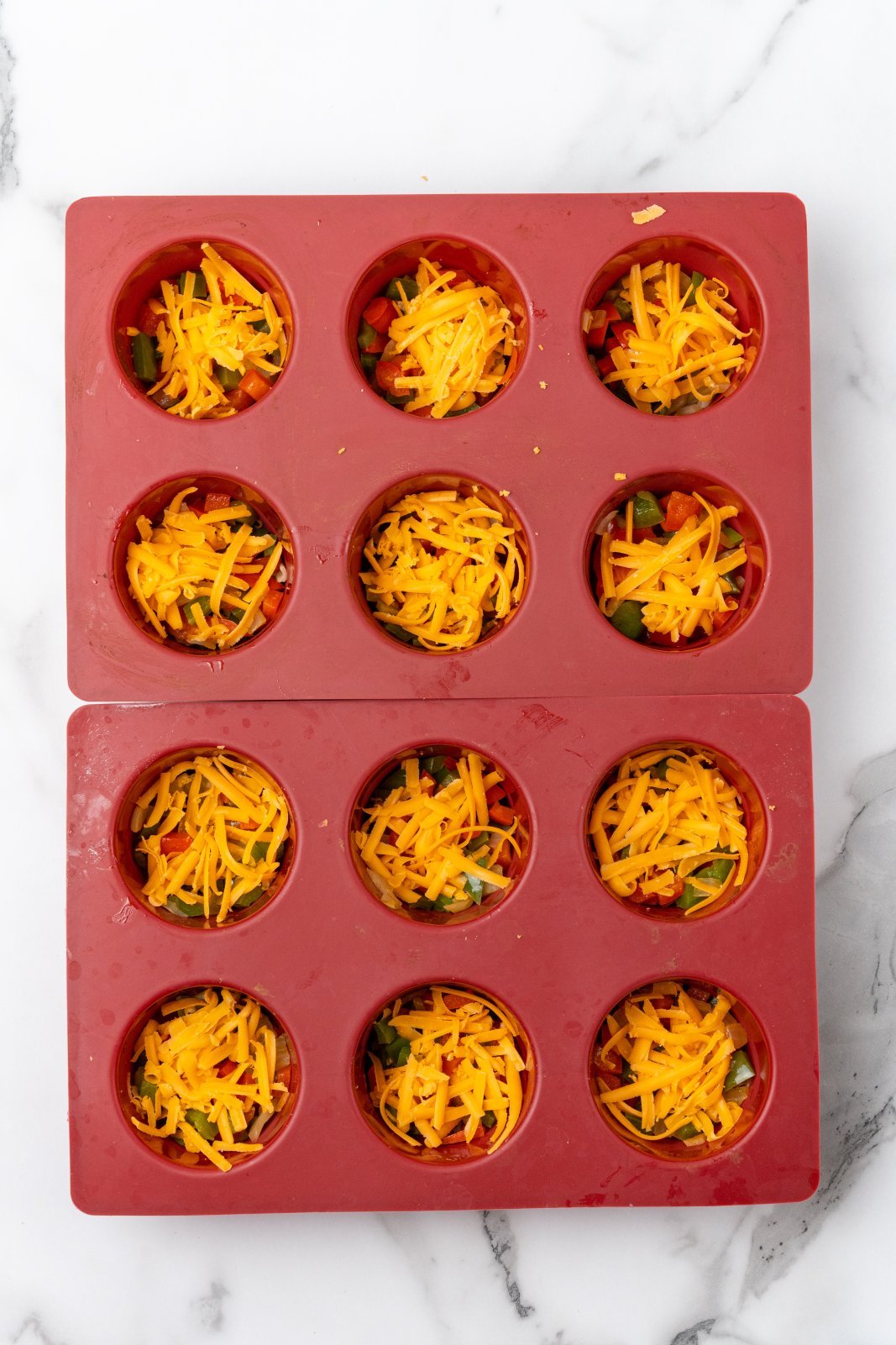 muffin tins with onion and pepper and cheese inside