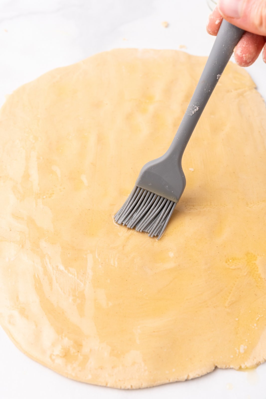 butter being brushed onto dough