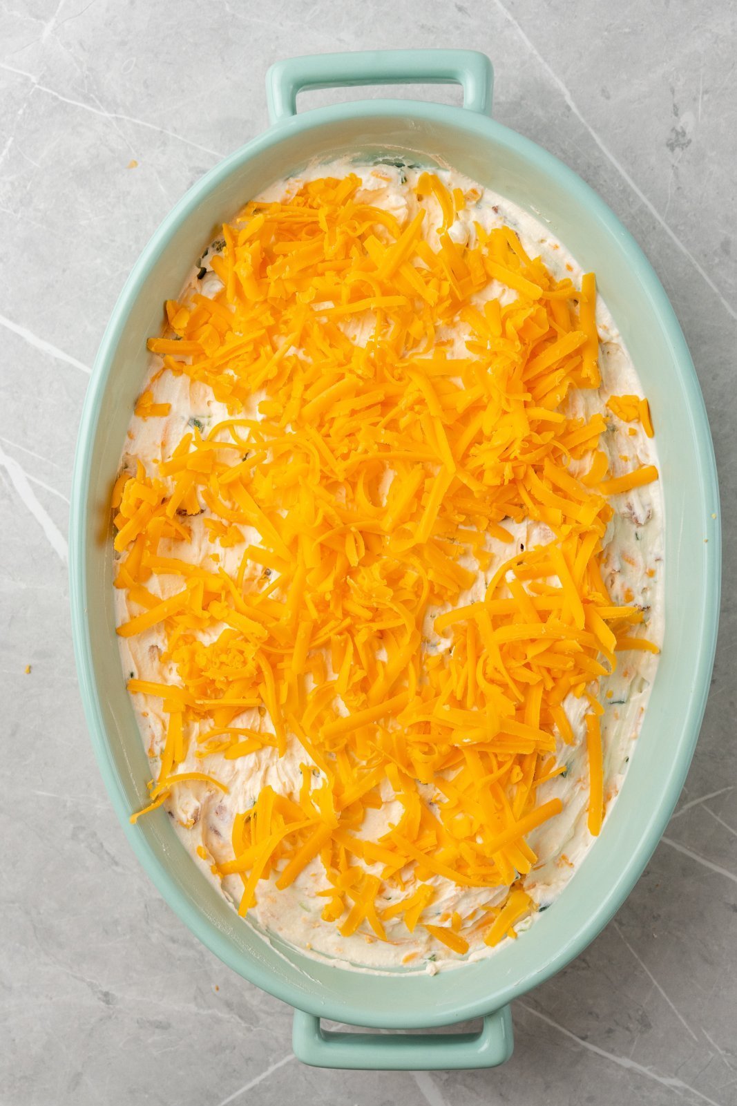 jalapeno popper dip in a dish topped with cheddar cheese
