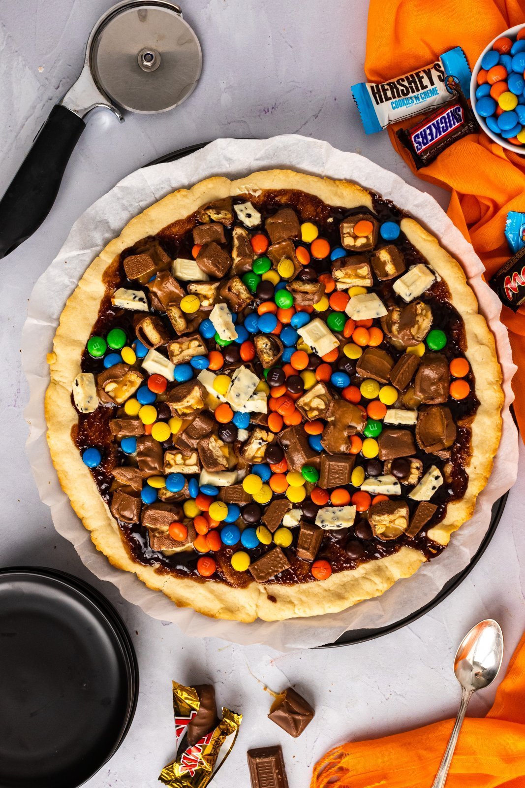 Halloween Candy Cookie Pizza shown with extra chocolates scattered around