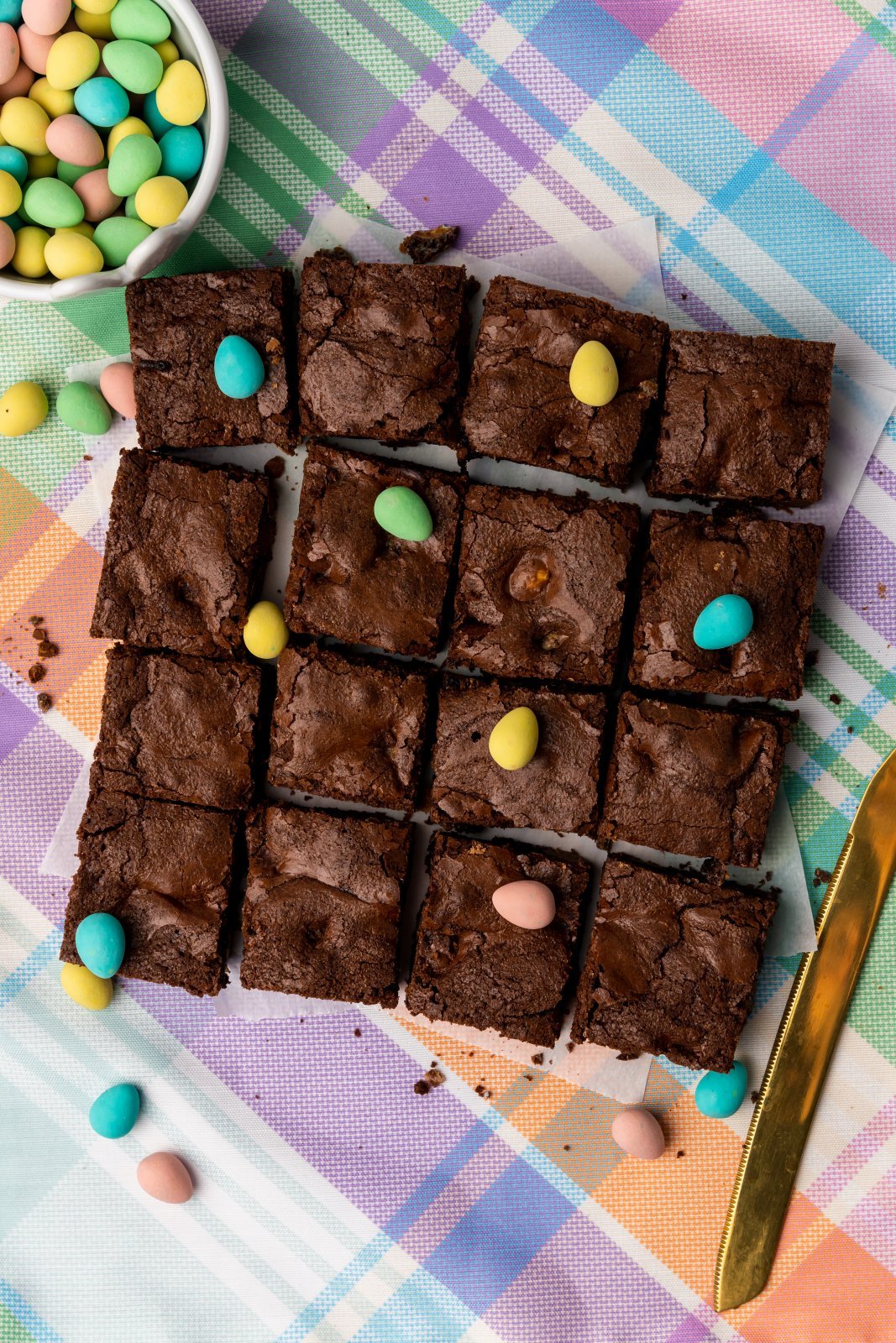 the mini egg brownies are sliced into squares on top of a pastel plaid backgroud