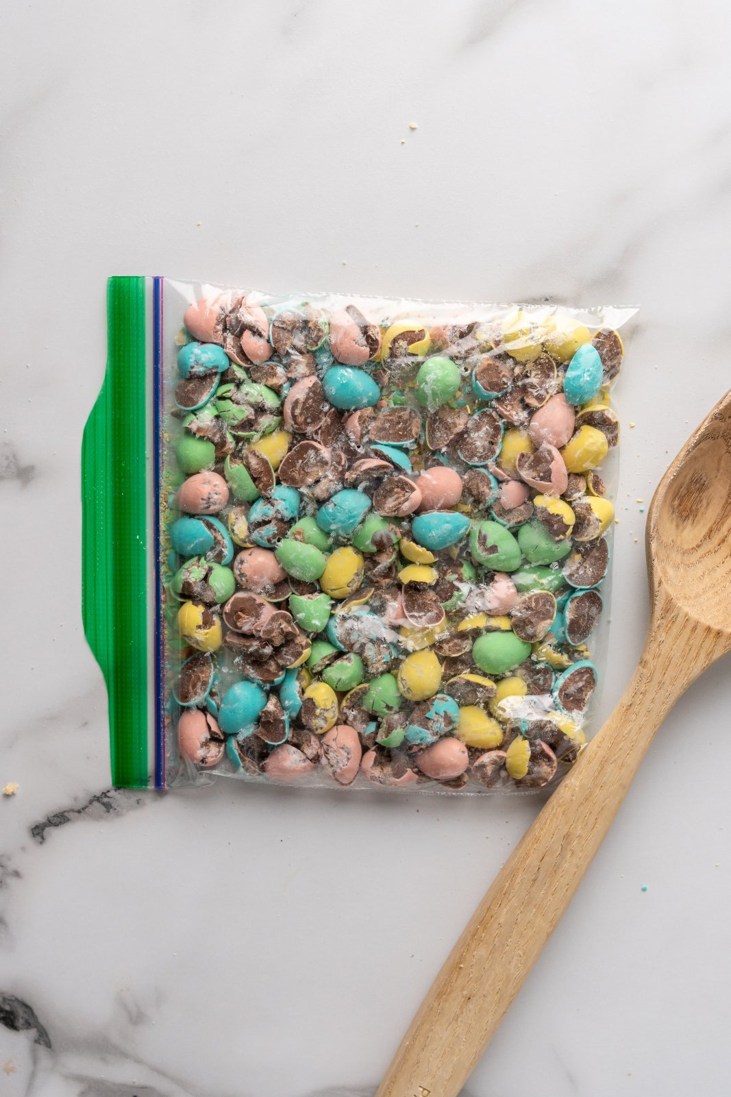 a bag with crushed mini eggs and a wooden spoon beside it