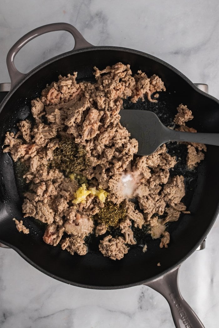 partially cooked turkey is shown in a skillet with seasonings