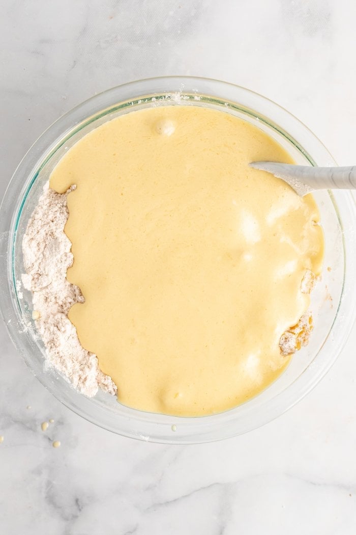 a bowl showing the wet ingredients added to the dry ingredients for peach cobbler muffins