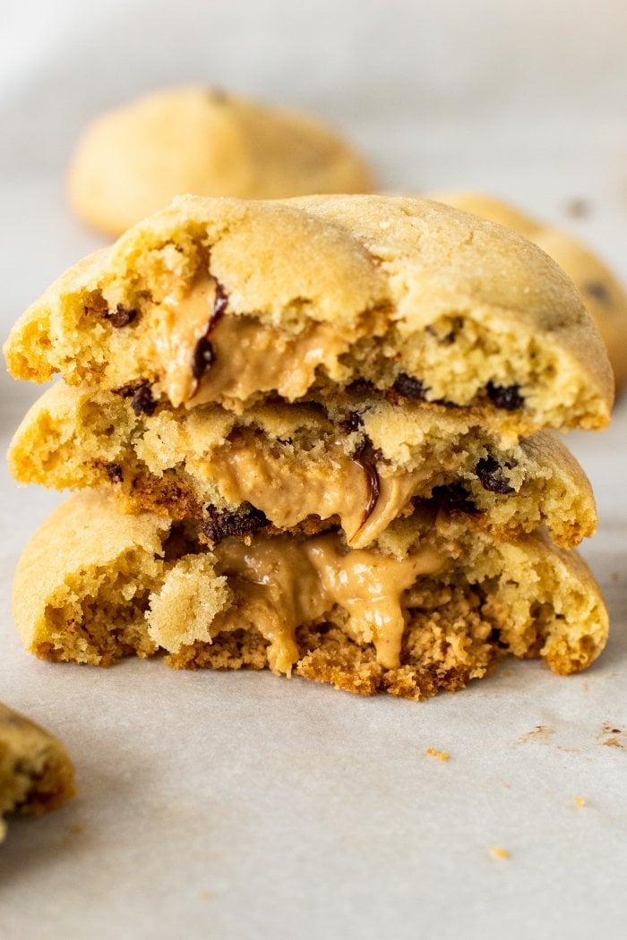 three peanut butter cookie halves are stacked on top of each other, melted peanut butter oozes out